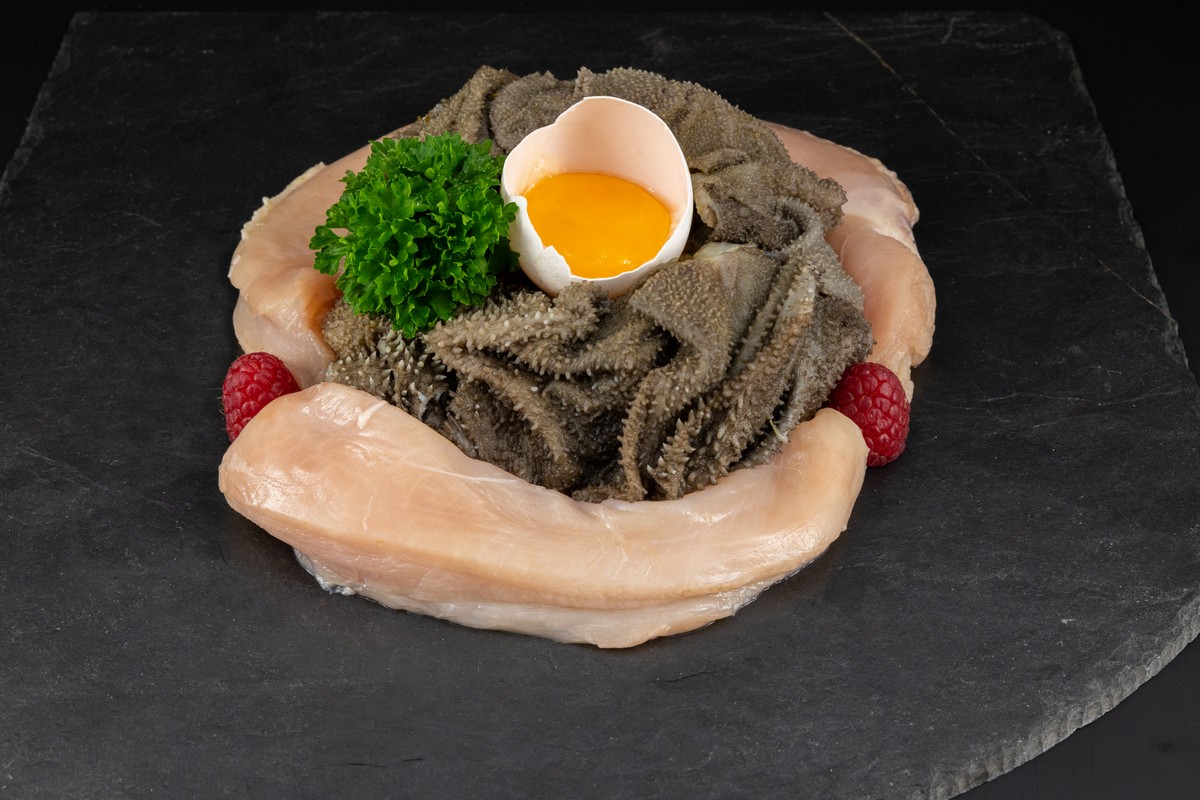 das bild zeigt ein arragement von pansen, fleisch, ei und kräutern, als beispiel für eine barf-fütterung