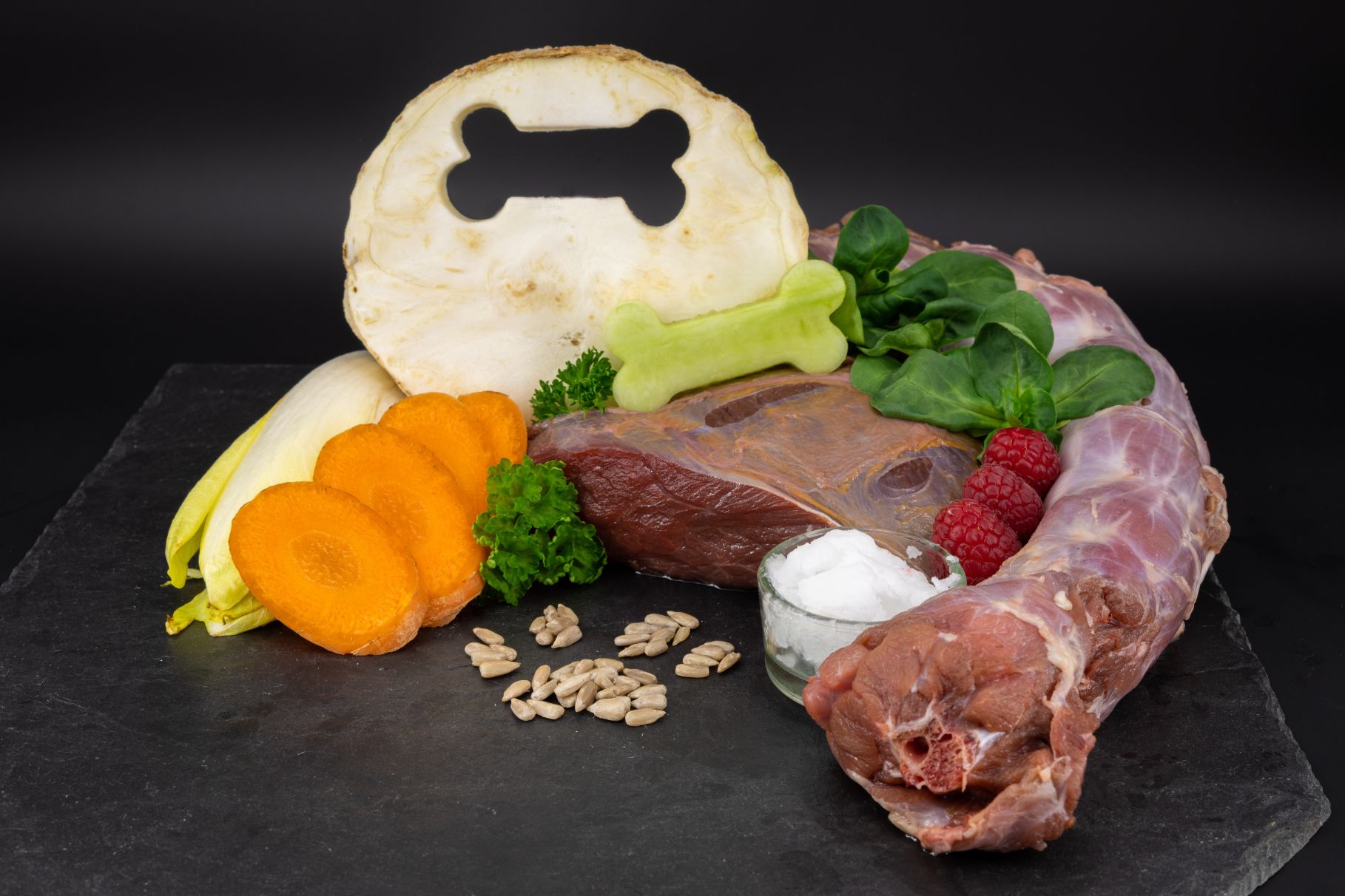 Das Bild zeigt ein Arrangement von Fleisch, Obst, Gemüse, Kräutern, Fett und Fleisch, als Beispiel für eine barf-Fütterung